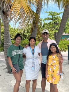 新万博移动客户端Collibra高级软件工程师Vidhya Sitaraman与她的丈夫和两个女儿在热带地区微笑