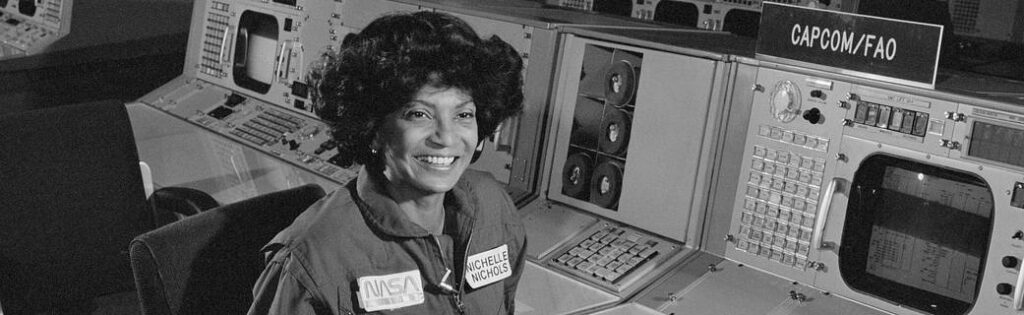妮切尔·尼科尔斯微笑着坐在美国宇航局的电脑板后面